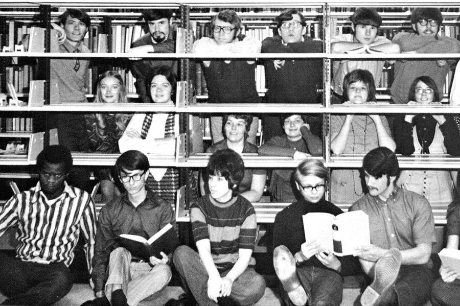 Photo dated 1971, students in front and behind book shelves in the library.