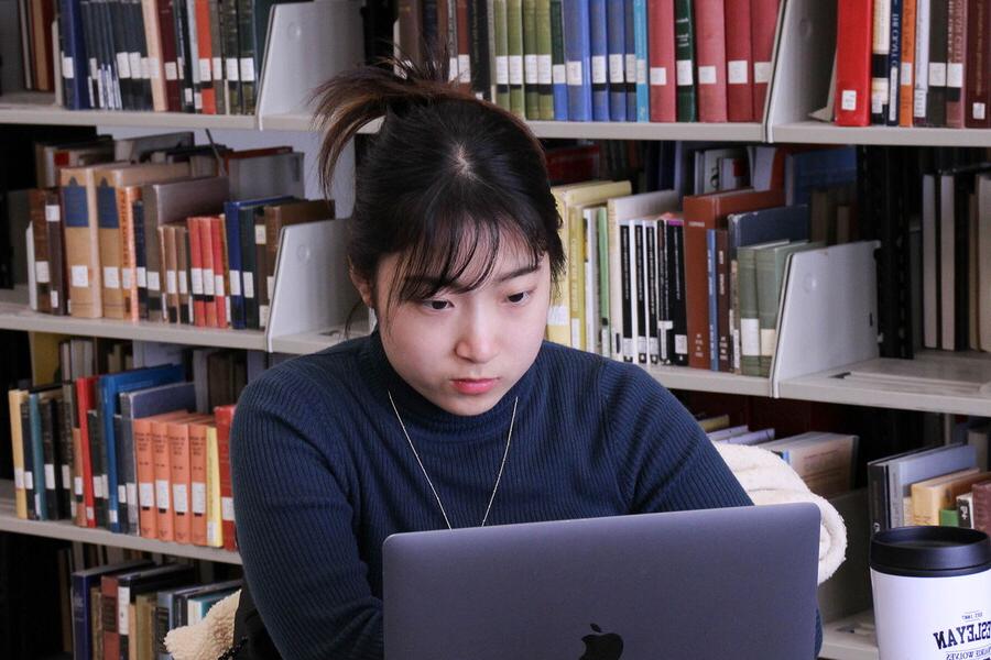 一个年轻女人在图书馆用笔记本电脑.